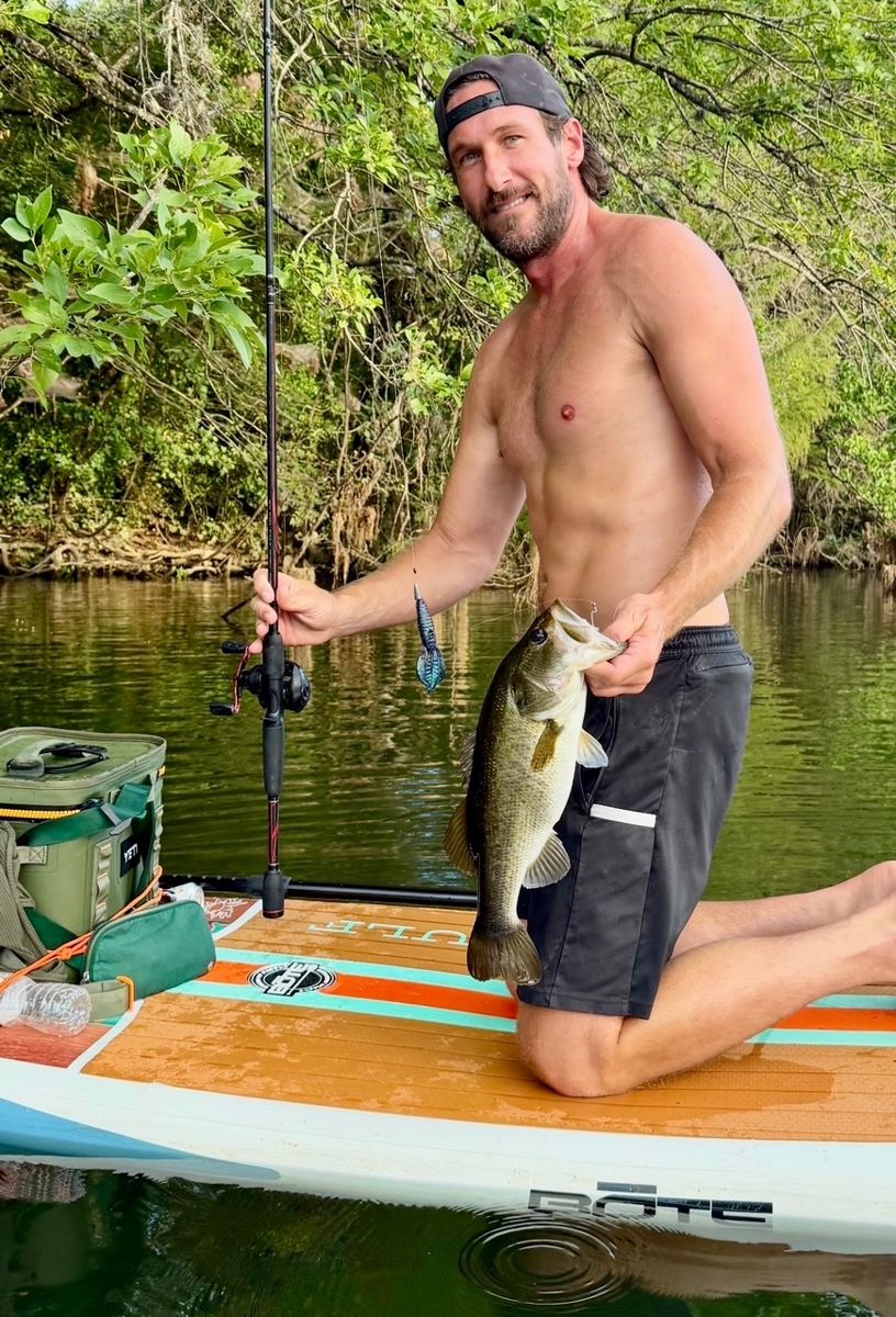 Phil Doubek holding a largemouth bass on a paddleboard